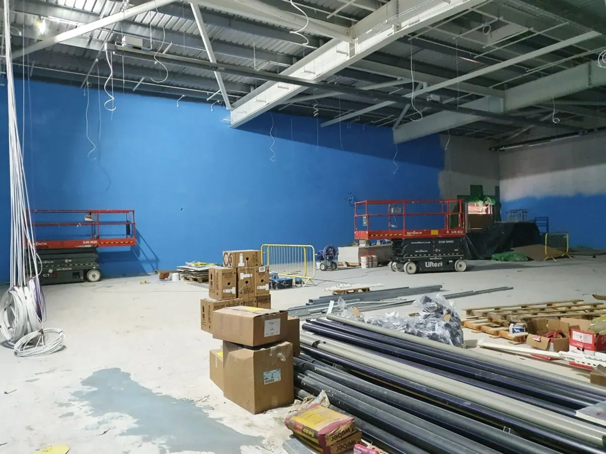 Large commercial space with bold blue walls and multiple scissor lifts during painting works