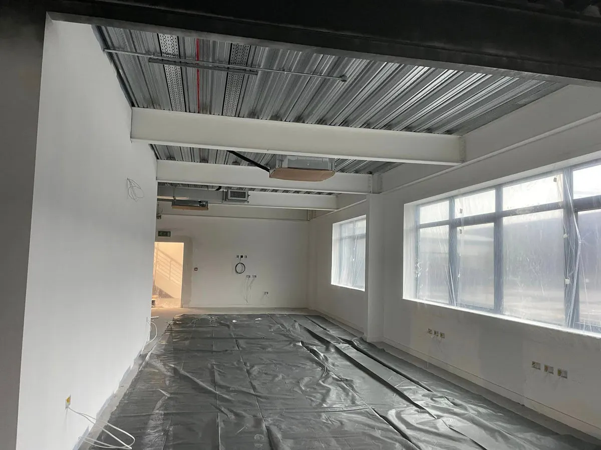 Freshly painted white office interior with polished floor sheeting down and windows covered with plastic