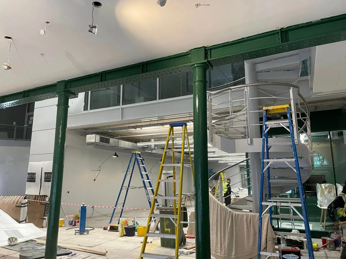 Heritage commercial building interior with green painted steel columns spiral staircase and ladders