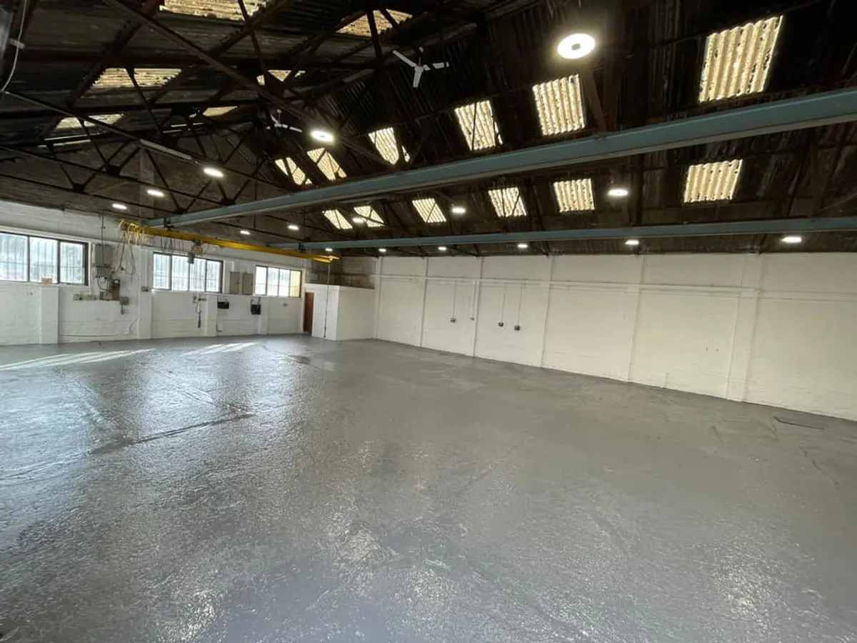 Completed industrial warehouse with white painted walls grey floor coating and overhead crane beam