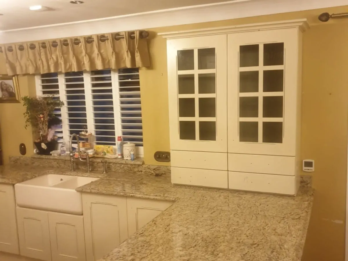 Cream sprayed kitchen with Belfast sink granite worktops and glass-fronted larder cupboard