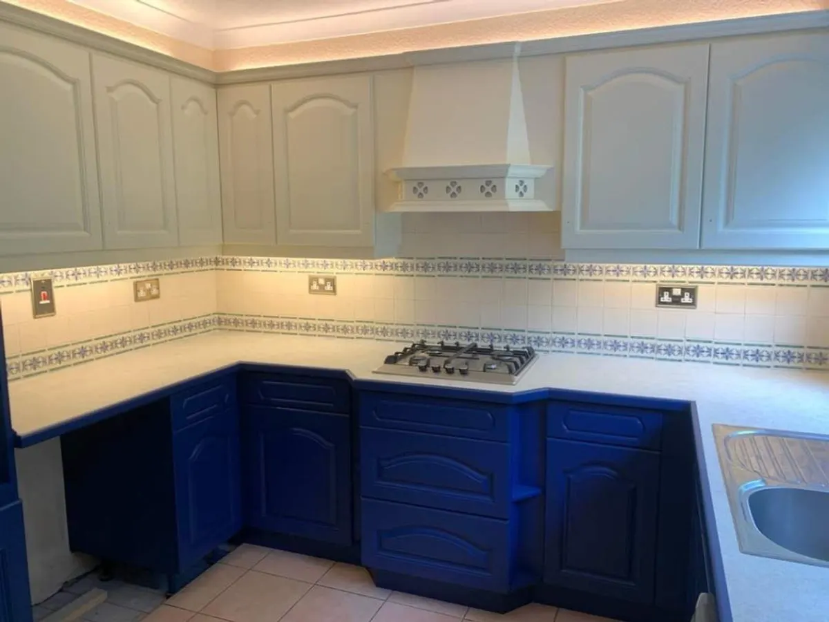 Completed kitchen with royal blue sprayed base units cream wall cabinets and decorative tile border