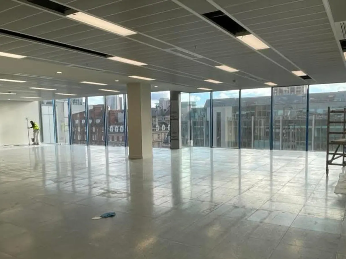 Large open-plan commercial office floor being painted with floor-to-ceiling windows and city views